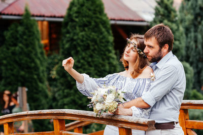 Couple holding bouquet standing outdoors