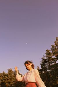 Low angle view of woman standing against clear sky