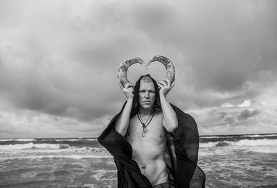 Low section of man standing on beach against sky