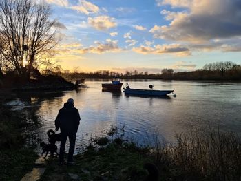 Silhouette man on boat against sky during sunset