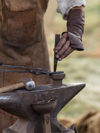 Midsection of blacksmith working at workshop