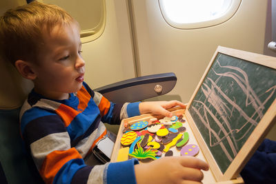 Boy playing with toy while sitting in airplane