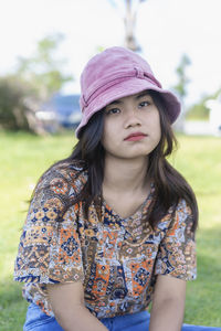Depressed young woman looking at camera sitting in the park. outdoor portrait of a sad teenage girl 