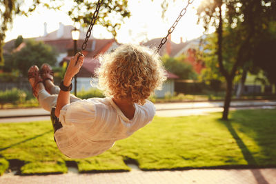 Rear view of woman swinging in park