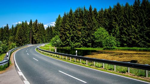 Road by trees against sky