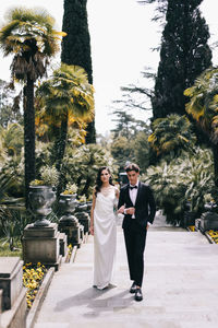 Young couple standing by trees against plants