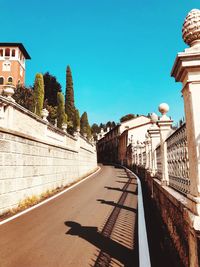 Street amidst buildings against clear blue sky