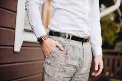 Midsection of man holding umbrella standing against blurred background