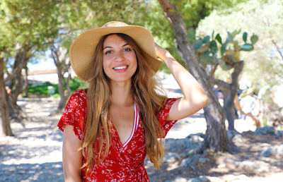 Portrait of smiling young woman wearing hat while standing on land