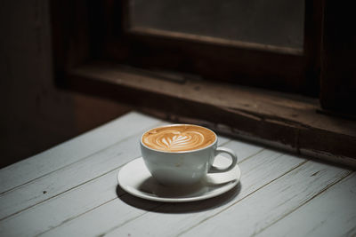 Latte art coffee on wooden table in coffee shop