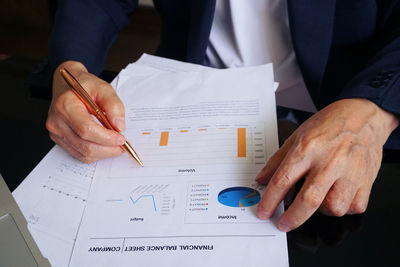 Midsection of man holding paper