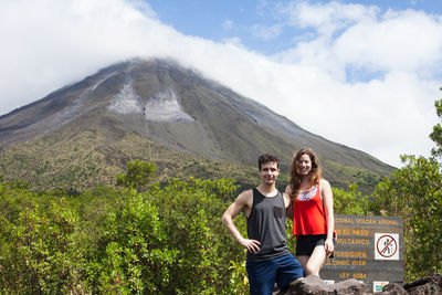 Young couple standing by sign against volcano