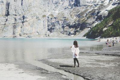 Full length of woman standing against lake during sunny day