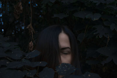 Portrait of young woman with leaves in sunlight