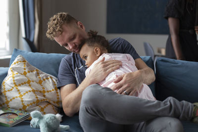 A father holding his young daughter on the couch