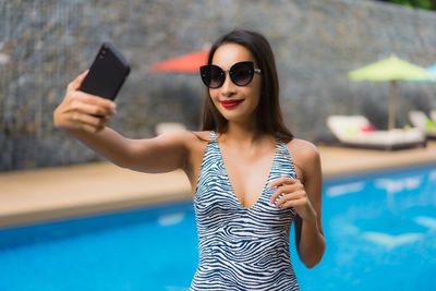 Portrait of young woman using smart phone at swimming pool