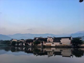 Buildings by lake against sky