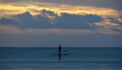 Silhouette man on sea against sky during sunset