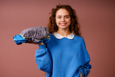 Portrait of young woman standing against yellow background