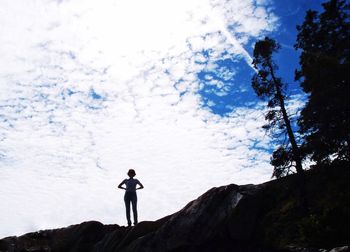 Low angle view of woman standing on mountain against sky