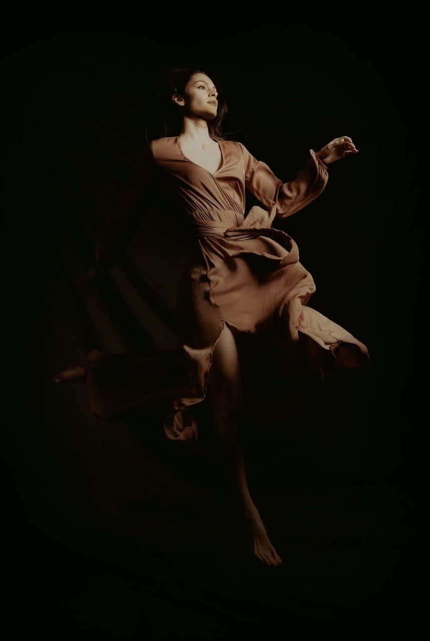 full length, black background, studio shot, dancing, one person, indoors, performance, skill, young adult, arts culture and entertainment, women, motion, adult, clothing, young women, performing arts event, elegance, jumping, blurred motion, dark, human arm, stage, arms raised, beautiful woman