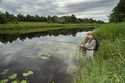 Man sitting on grass by lake