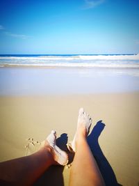 Low section of people on beach against sky