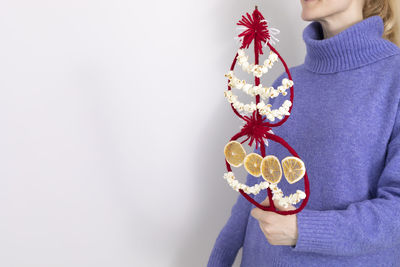 Midsection of woman with bouquet against white background