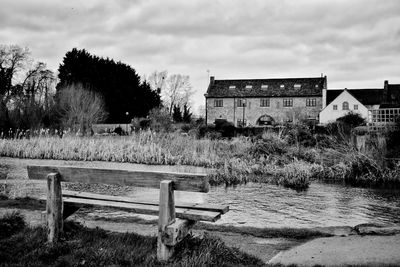 Empty bench on field by building against sky