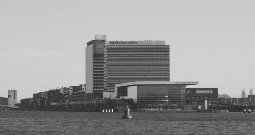 Modern buildings by sea against clear sky