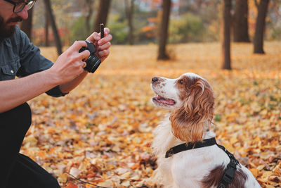 Man photographing dog through camera in park during autumn