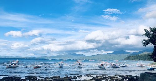 Sailboats moored on sea against sky