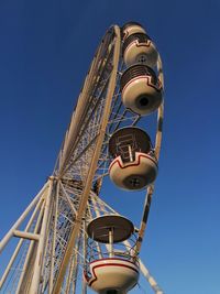 Low angle view of ferris wheel against clear blue sky