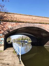 Arch bridge over river against blue sky