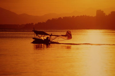 Silhouette seaplane on sea during sunset