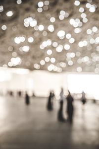 Defocused image of people walking on illuminated street at night