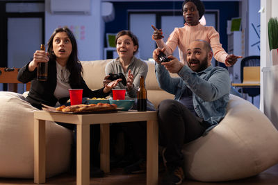 Excited friends playing video game at office