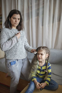 Mother combing daughters hair