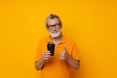 Senior man gesturing while holding coffee cup