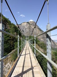 Footbridge amidst plants against sky