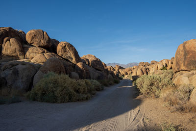 Rock formations on road amidst rocks against sky