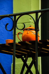 Close-up of yellow metal railing against blue fence