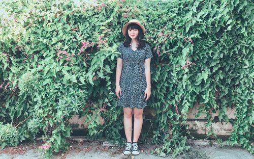 Portrait of young woman standing against plants