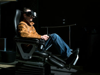 Side view of man playing virtual reality game on seat