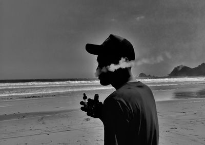 Man standing at beach against sky