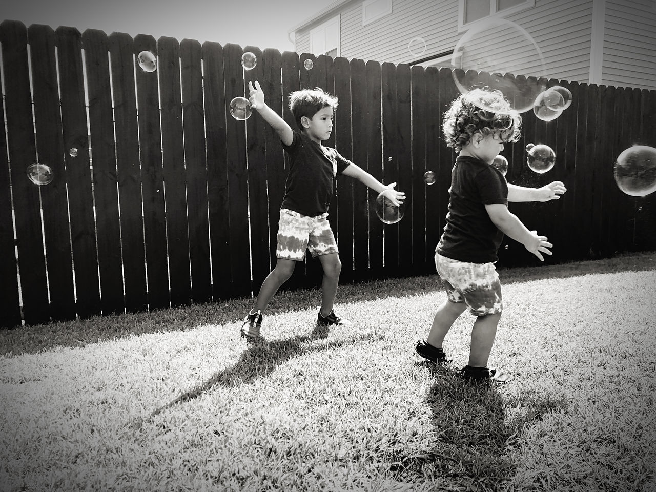 black, white, black and white, child, monochrome, childhood, full length, monochrome photography, men, sports, ball, soccer, two people, motion, fun, togetherness, lifestyles, leisure activity, female, person, adult, casual clothing, playground, women, day, team sport, nature, friendship, darkness, soccer ball, outdoors