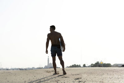 Rear view of shirtless man walking on street