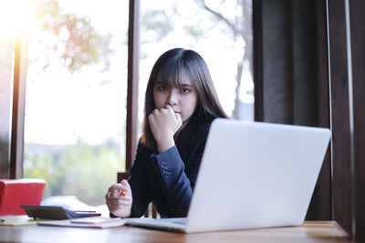 Portrait of woman sitting on table at home