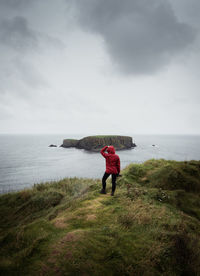 Rear view of man standing on sea shore against sky