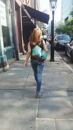 Rear view of woman standing on sidewalk